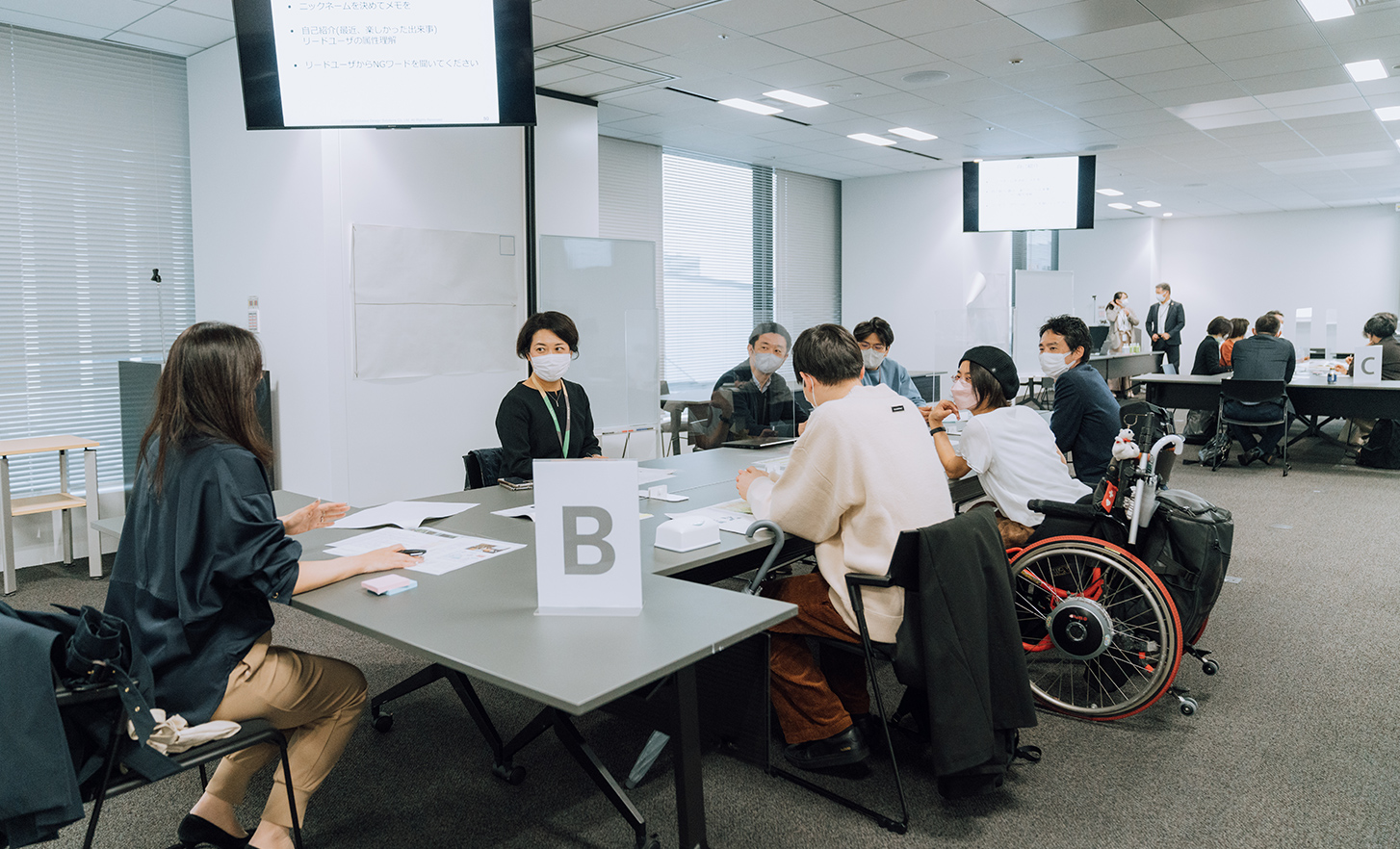 Des employés et une personne en fauteuil roulant assis autour d’une table discutent