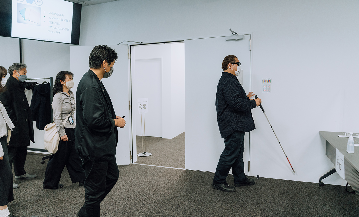 Employés observant l’utilisateur de référence avec une canne blanche marchant dans la salle de conférence