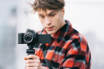 Image of a man holding the base of a camera’s grip while looking at the camera’s monitor