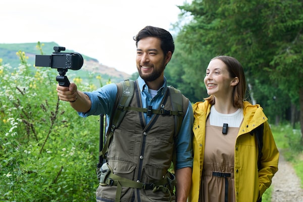 Photographie d’un homme et d’une femme portant un microphone et souriant en direction d’une caméra dotée d’un récepteur