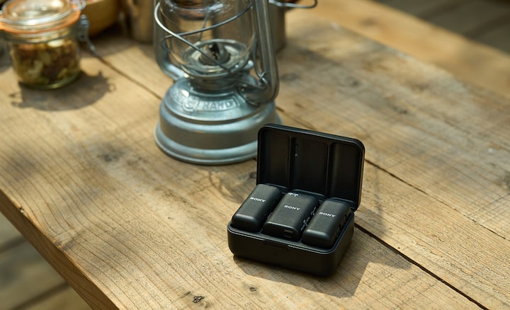 Image des deux microphones-émetteurs et du récepteur dans le boîtier de recharge, sur une table en bois