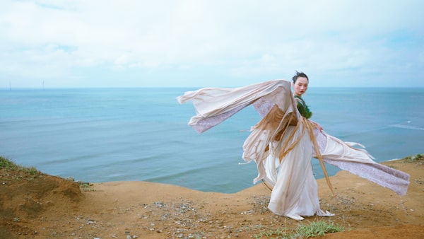 Image d’une femme en tenue d’époque, avec le bord de mer en arrière-plan