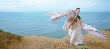 Image d’une femme en tenue d’époque, avec le bord de mer en arrière-plan