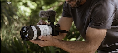 Photo d’un homme filmant une vidéo avec un microphone fixé à l’appareil photo