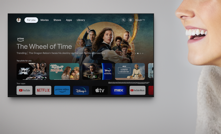 Wall-mounted television showing a variety of entertainment apps and selected shows with woman’s head to the right