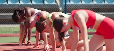 Image de quatre athlètes au départ d’une course féminine de saut de haie, la mise au point est faite sur la troisième athlète la plus proche de l’appareil