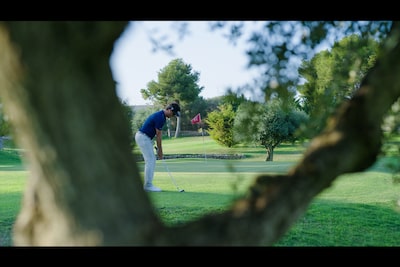 Image d’illustration d’un joueur de golf mis au point avec un tronc d’arbre défocalisé au premier plan