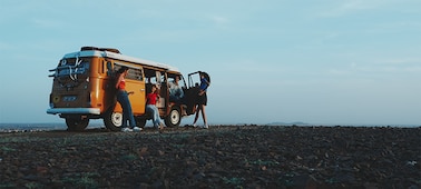 Exemple d’image de quatre personnes (hommes et femmes) discutant près d’une fourgonnette de camping orange