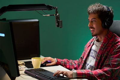 Image d’utilisation d’un homme portant des écouteurs reliés par un câble à un microphone, assis devant l’écran d’un PC