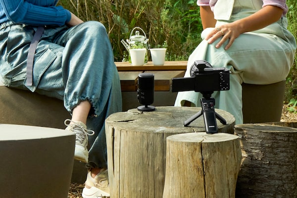 Image d’utilisation montrant deux personnes assises à l’extérieur, avec un microphone devant elles et une caméra à proximité avec un récepteur installé