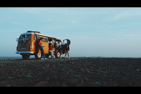 Exemple d’image de quatre personnes (hommes et femmes) discutant près d’une fourgonnette de camping orange