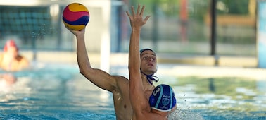 Image d’exemple montrant un homme essayant de jeter le ballon pendant un match de water-polo tandis qu’un autre homme défend en étendant une main, mais la mise au point reste sur l’homme à l’arrière