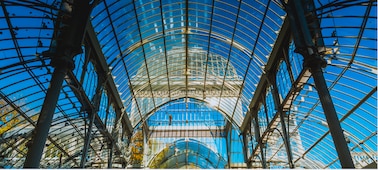 Interior shot of a glass building showing detail in architecture and blue sky beyond