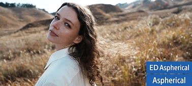 Portrait d’une femme regardant cet objectif dans un large champ couvert d’herbe-plume. Ses cheveux et l’herbe plume sont brillants, en plus de la mise au point portée à son œil gauche