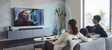 Family on a sofa watching TV with the HT-A7000 soundbar on a marble cabinet