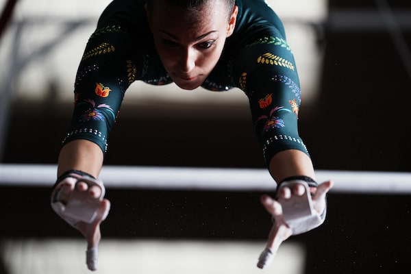 Image d’une gymnaste en plein élan, bras tendus entre les barres asymétriques